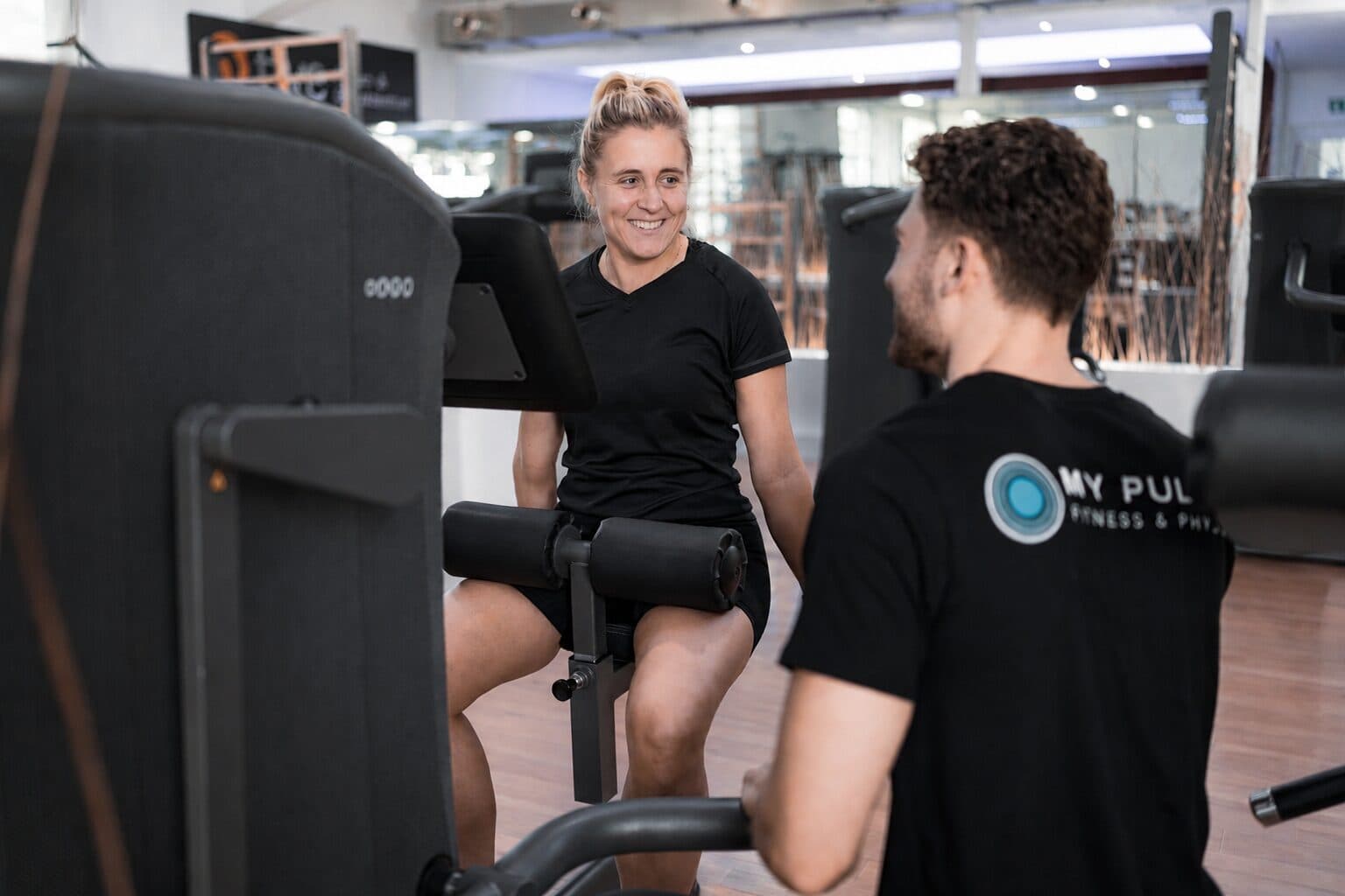 Trainer betreut ein Mitglied sicher am Gerät
