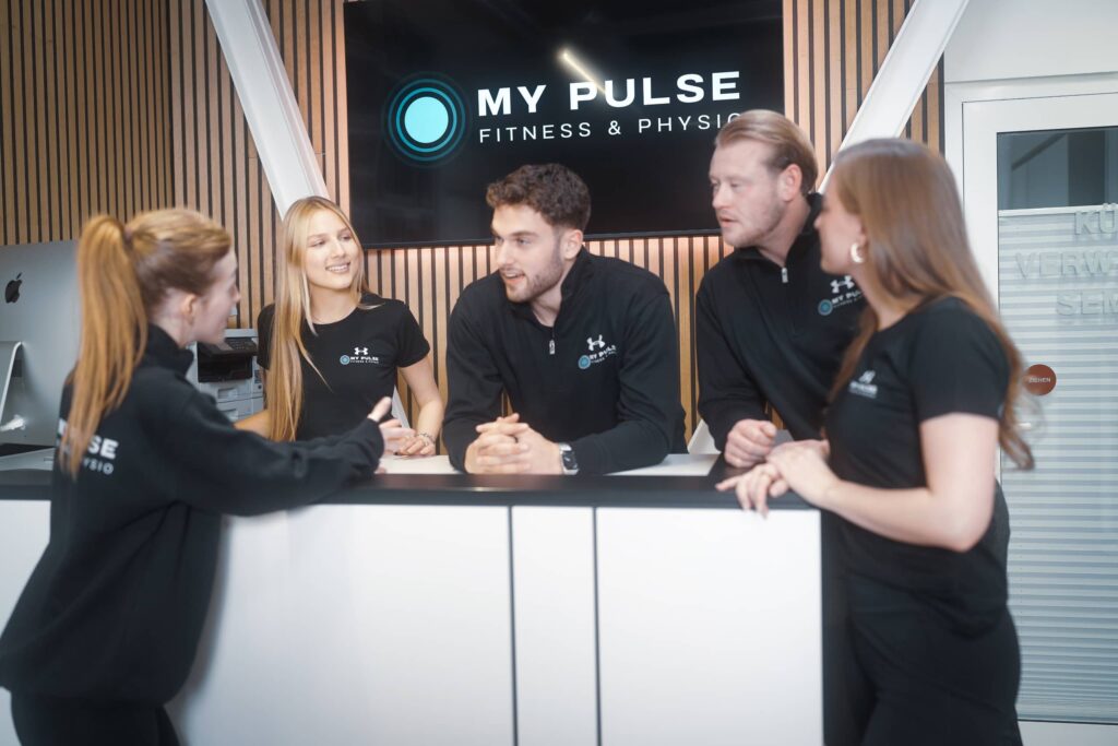 Studio-Team im Austausch an der Rezeption eines Fitness- und Physiostudios